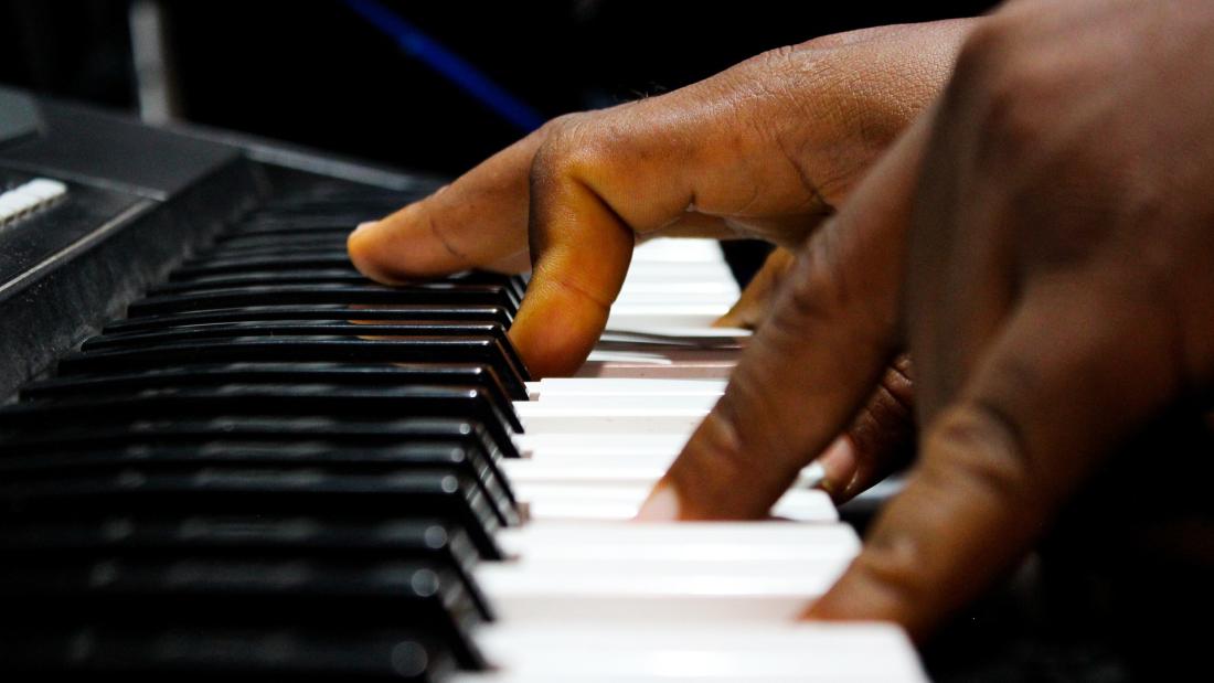  hands play piano keys.