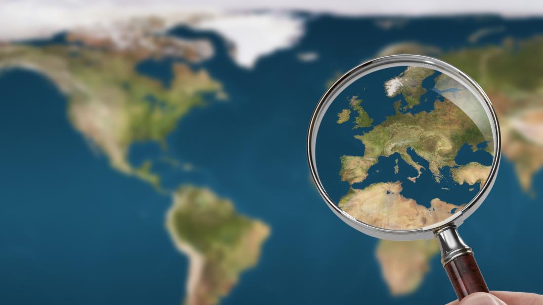 A map of the world with a magnifying glass lookig closer at Europe