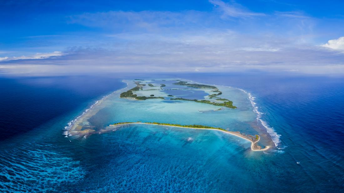An atoll sits in a blue ocean