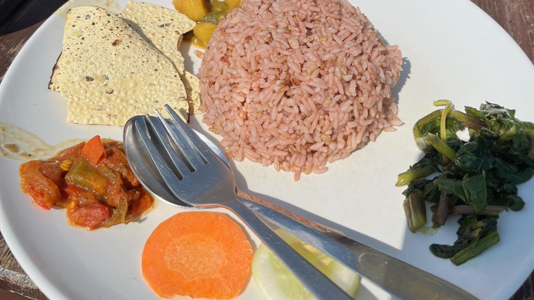 a plate, with knife and fork, including a portion of pink rice