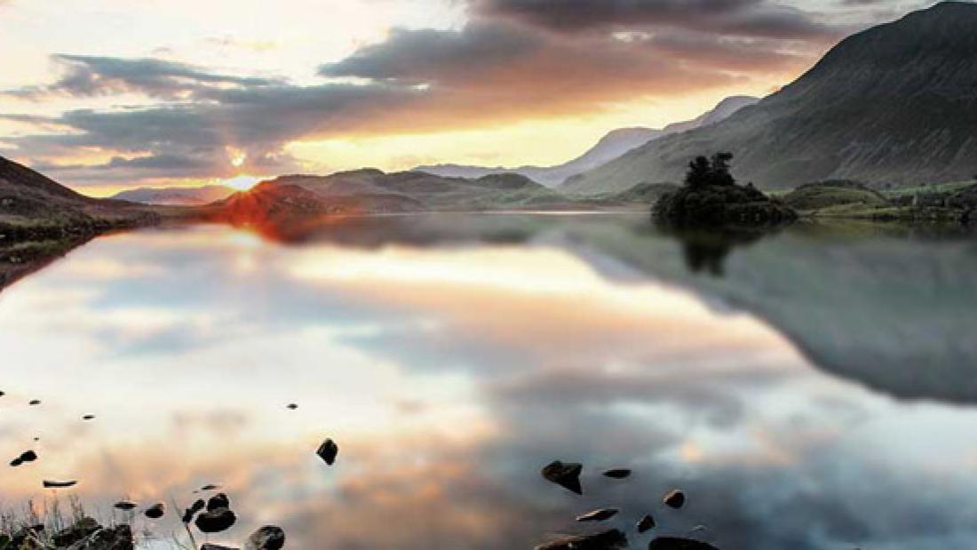 sunset over lake with mountains in the background