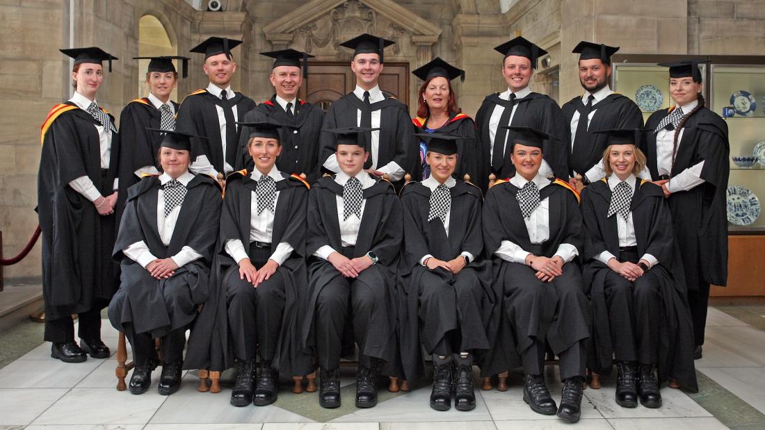 Police graduates in a group with graduation gowns