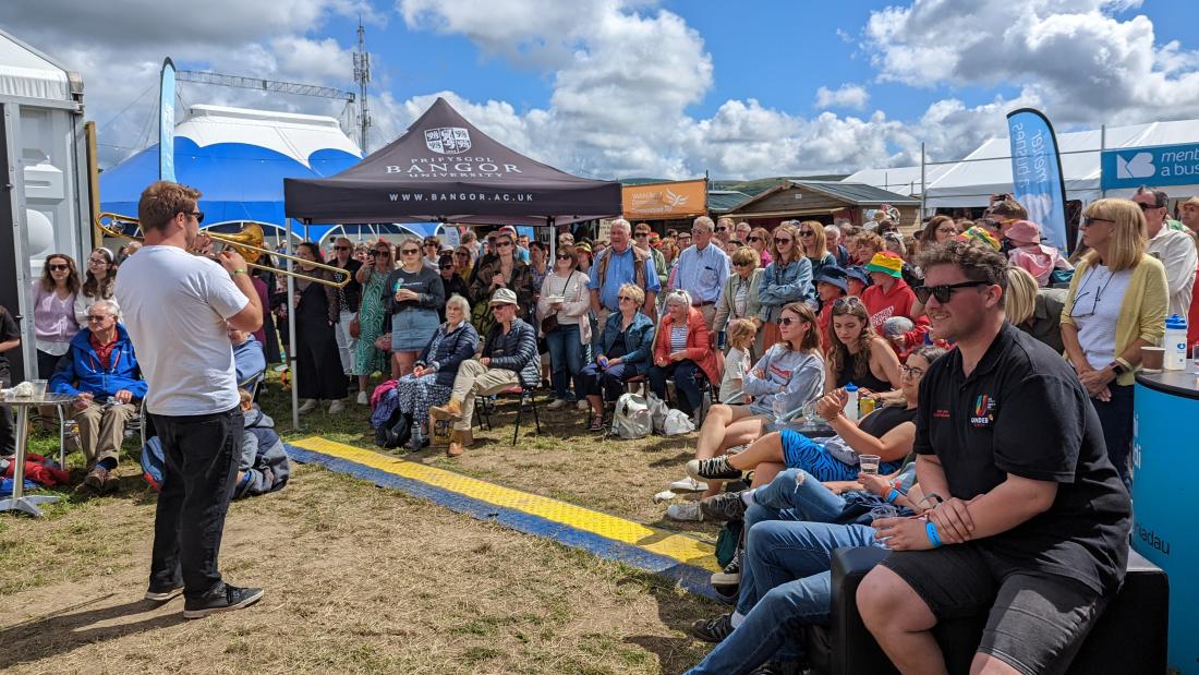  A crowd listens to performers outside under a blue sky