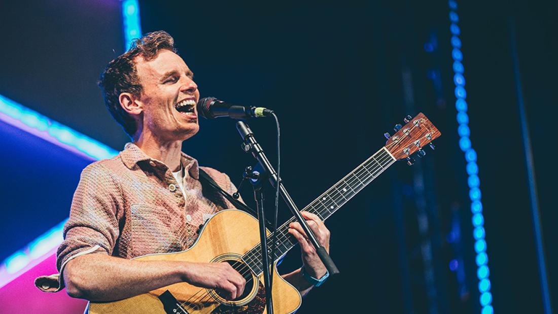 Person singing into a microphone and playing the guitar