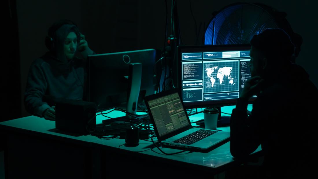 Two people sitting in front of computer screens in a dark room