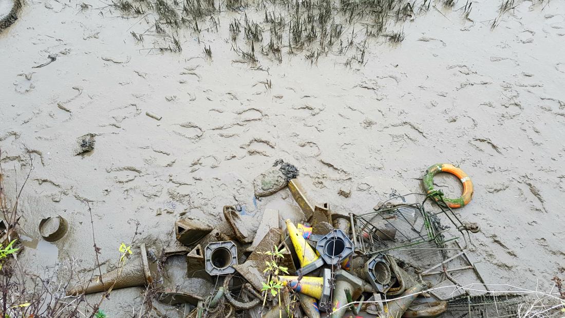 A muddy foreshore littered with rubbish