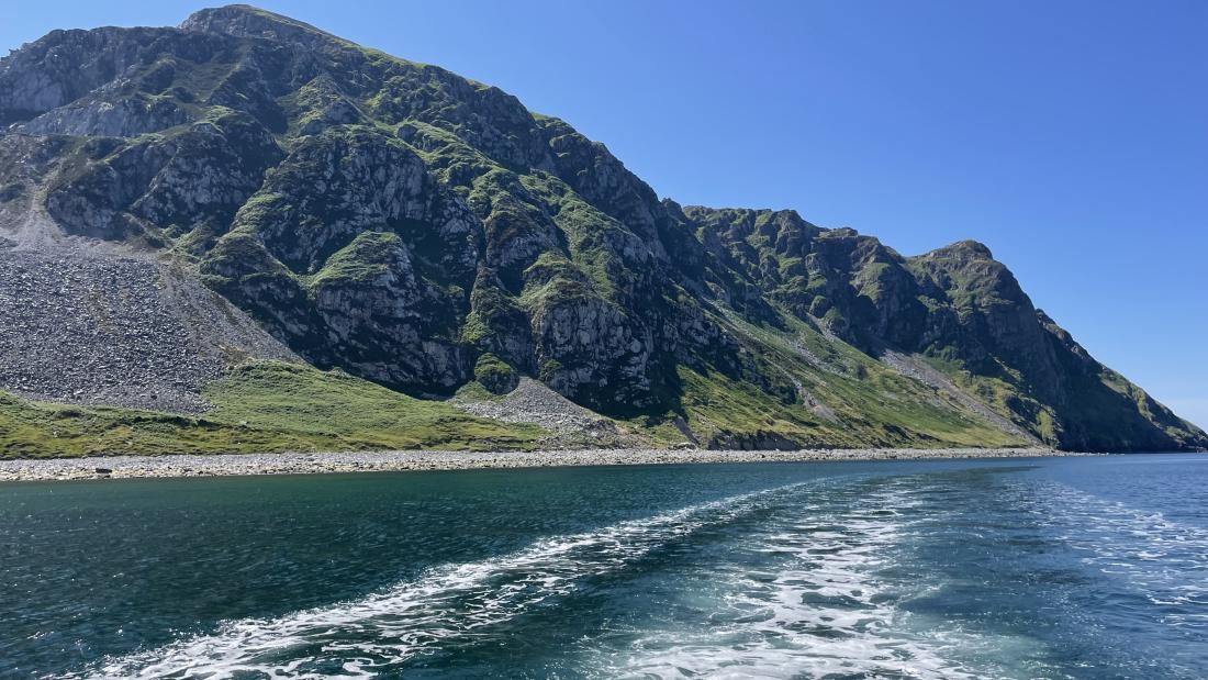Rocky cliffs seen from the stern of a boat 