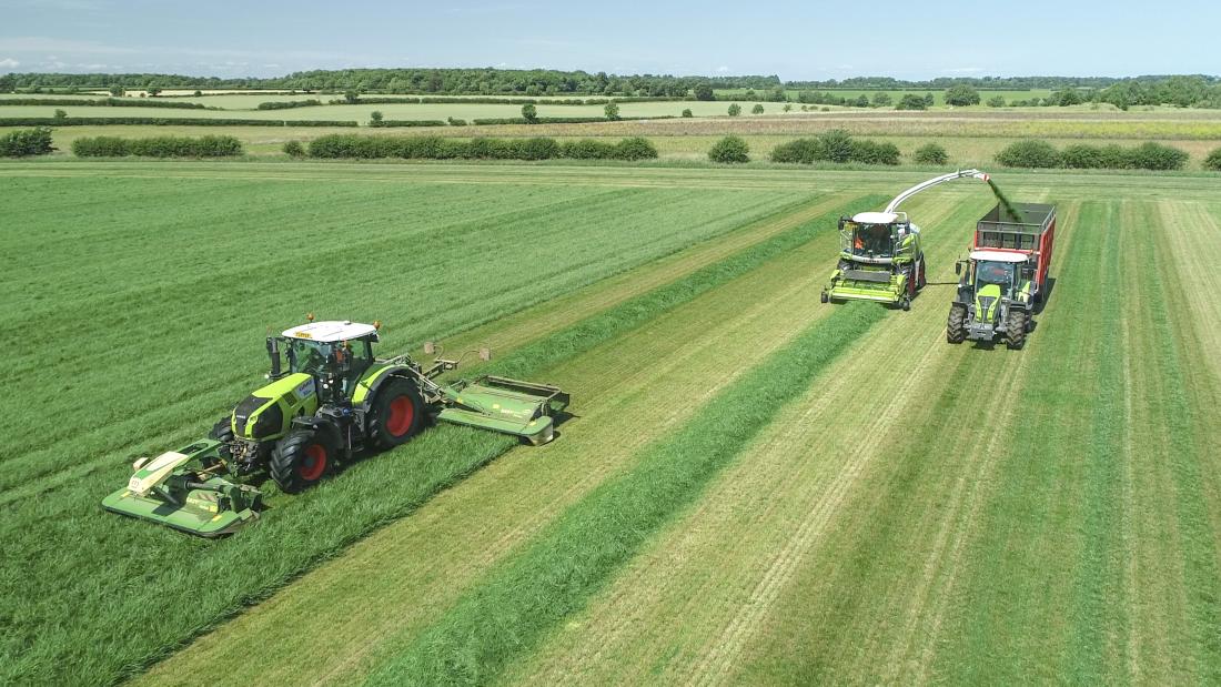 Harvesting grass in a field with three tractors