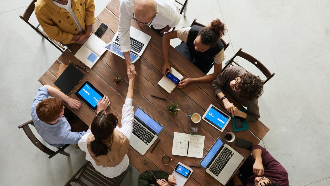 A group around a table with laptops and phones 