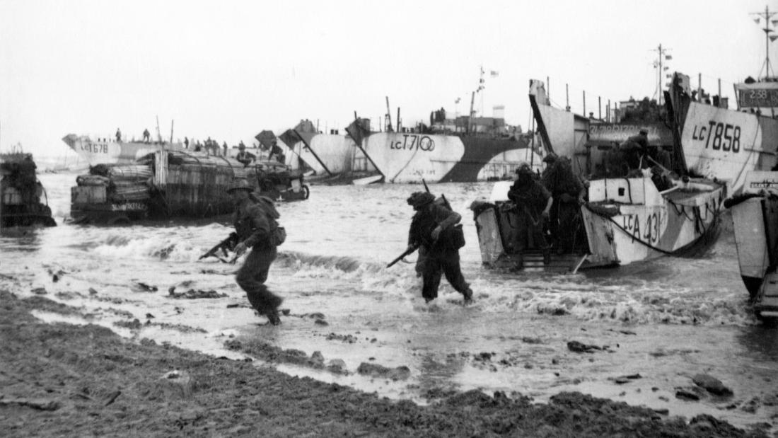 Black and white image of troops wading ashore from landing craft