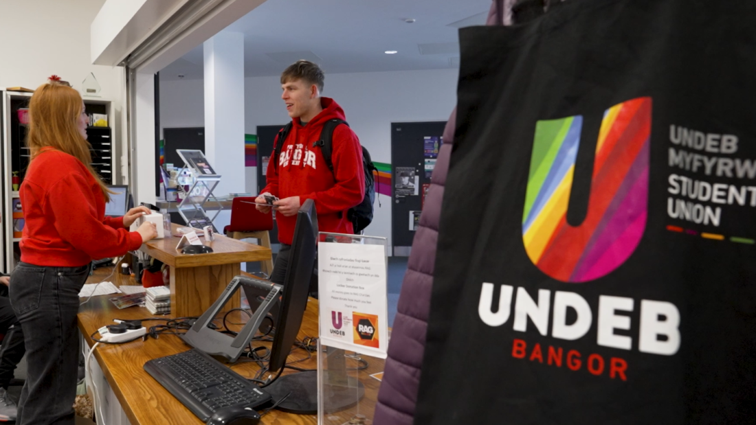 A student talking with a member of staff at the Undeb Bangor reception