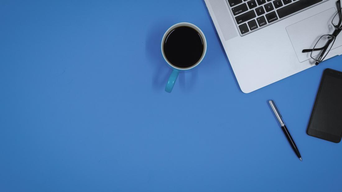 Desk with computer, mug, pen and notebook