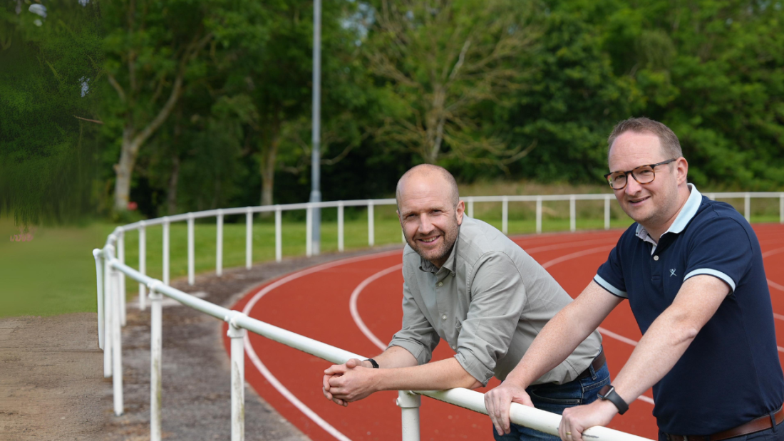 Two people standing on a racetrack looking at the camera