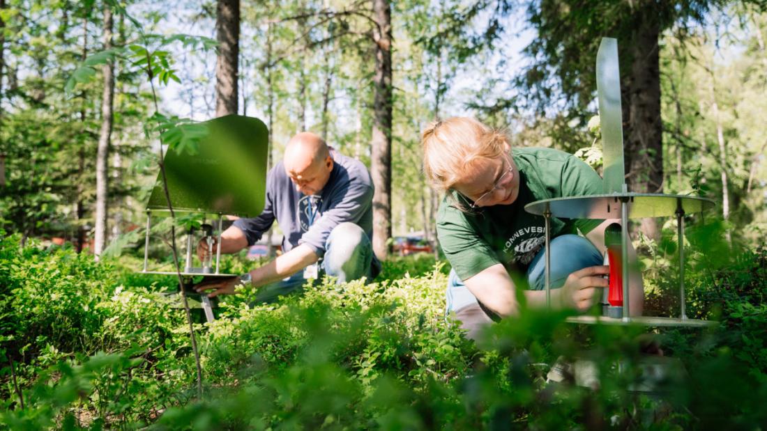  two people with  ground level contraptions in a wooded setting