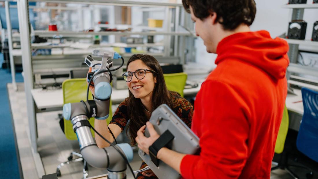 2 students looking at a robotic arm