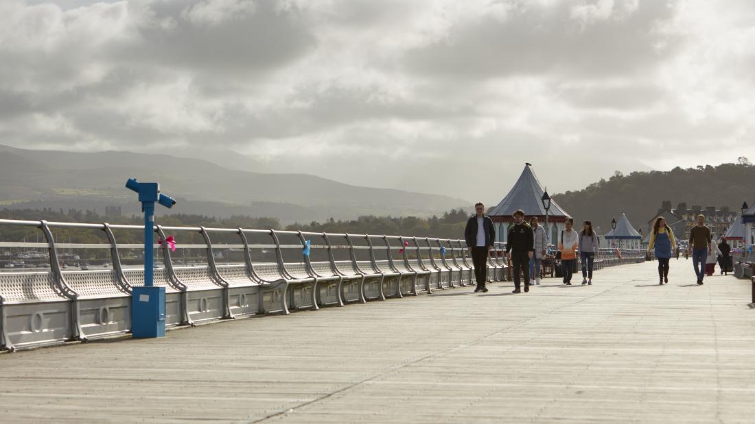 A group of students walking along Garth Pier in Bangor