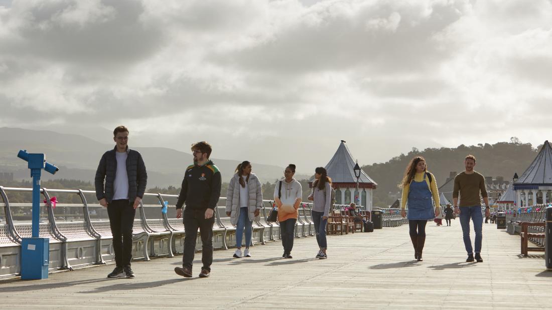 A group of students walking along Garth Pier in Bangor