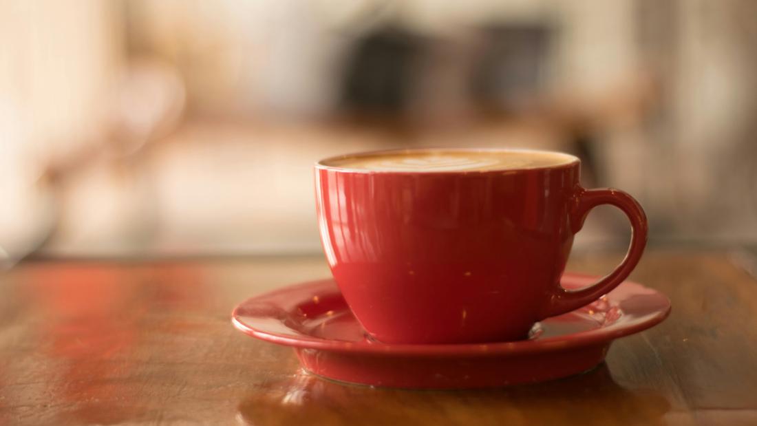 A cup of tea on a saucer, placed on a table