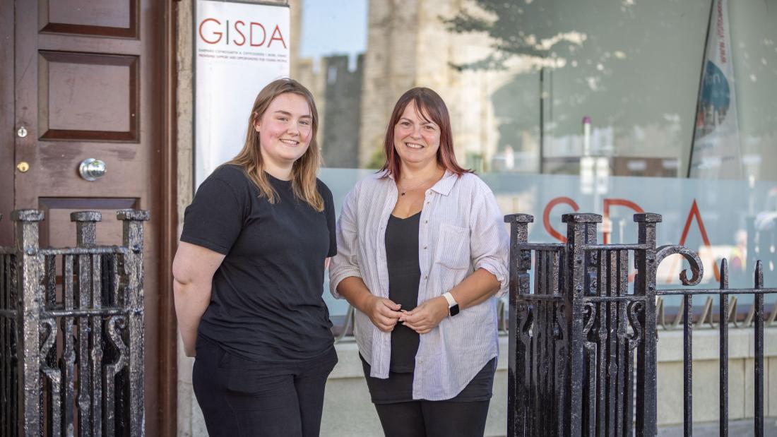 Two women smiling at camera with GISDA banner behind them