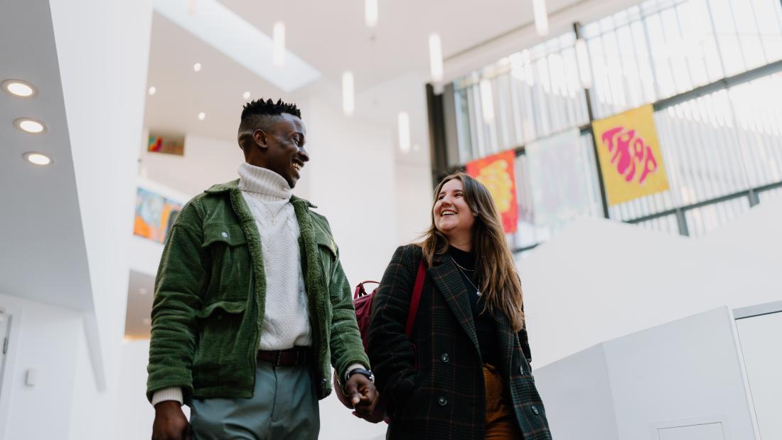 Two students walking whilst chatting to each other 