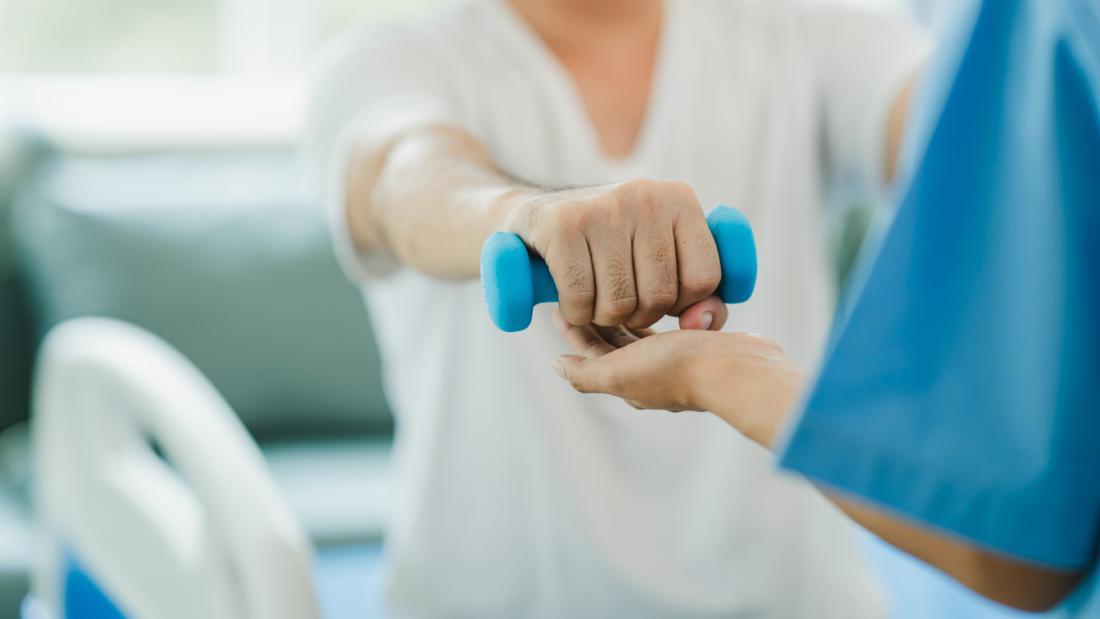 Person having rehabilitation holding a weight with an outstretched arm