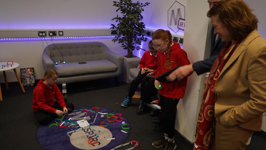 Welsh First MInister watching children play a game on a mat 