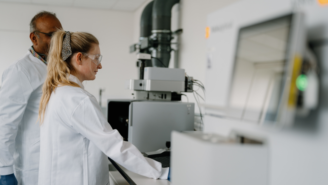 Two researchers in white lab coats looking at a screen at Bangor University's Nuclear Futures Institute