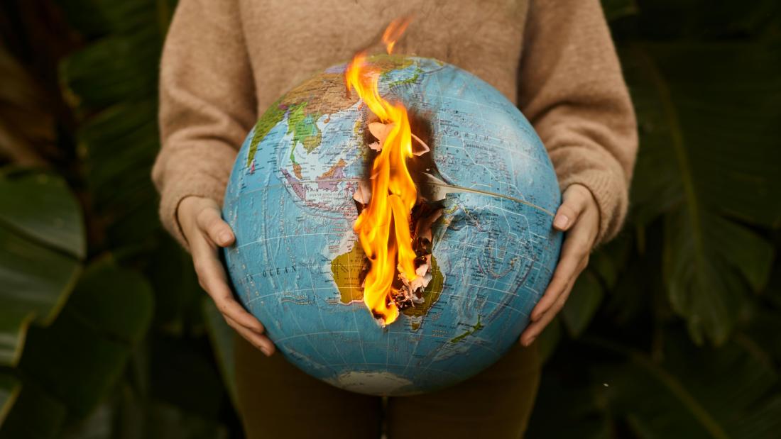 An individual holding the globe on fire