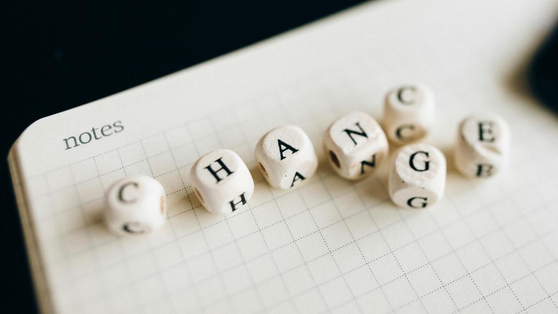 Notes paper with 7 white dice spelling out CHANGE