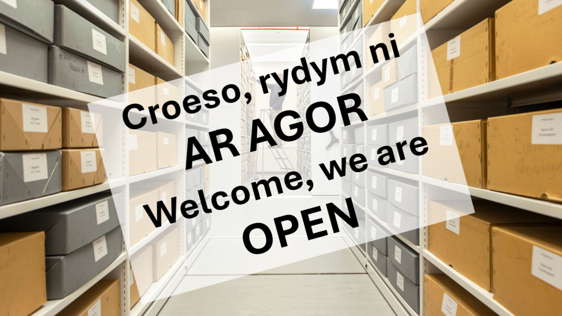 Sign saying: Welcome we are open against an archives backdrop