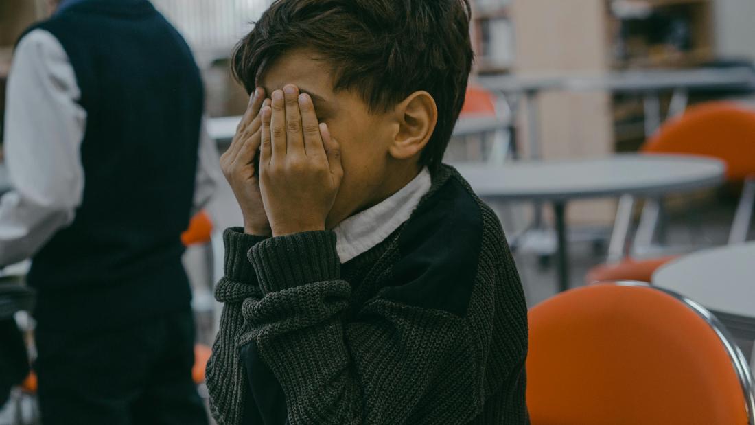 A Boy Covering His Face with His Hands