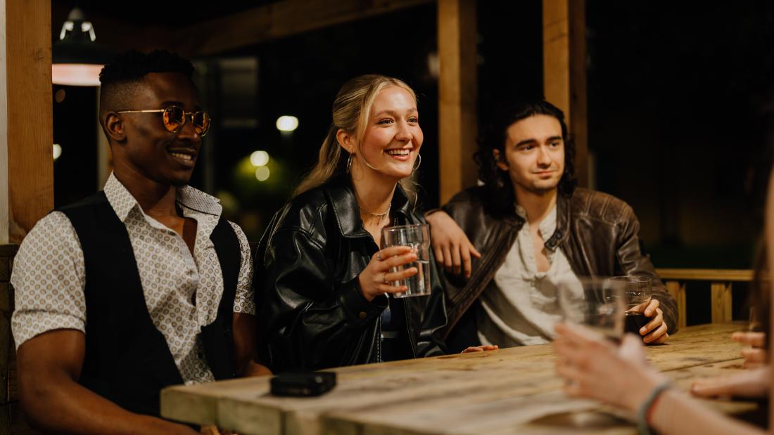 A group of students in an outside seated area, socialising and drinking soft drinks.