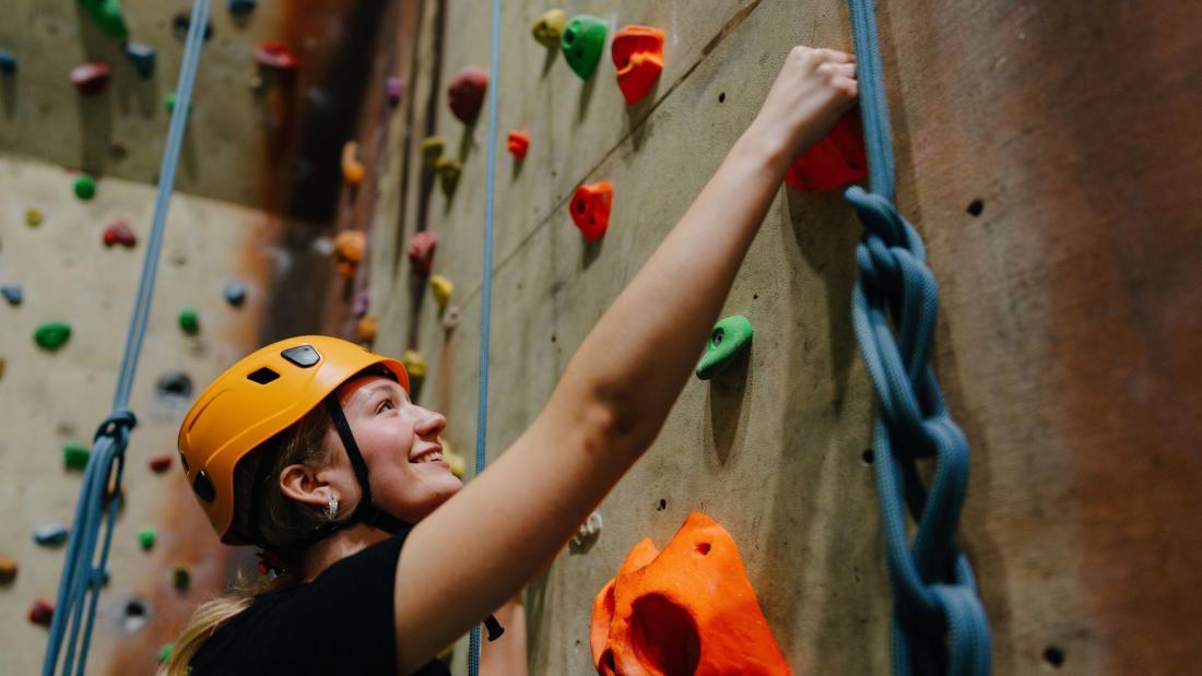 A student is climbing the climbing wall at Canolfan Brailsford