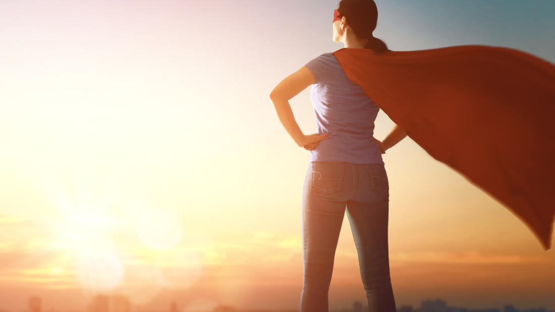 Back shot of a lady wearing a red cape looking into the distant land