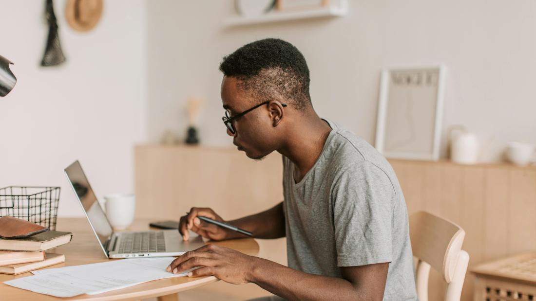 Man working in his kitchen on his laptop looking relaxed