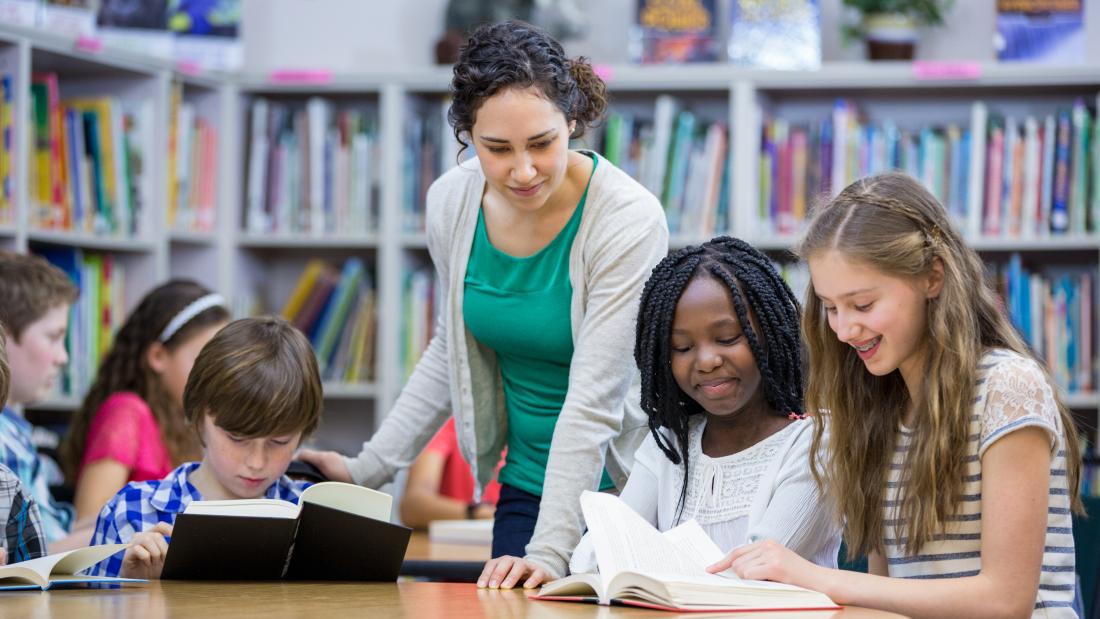 Children reading books with a teacher