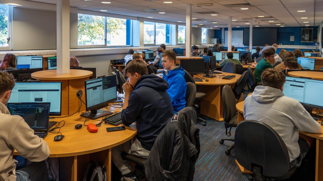 Computing lab with students looking at laptops in focus