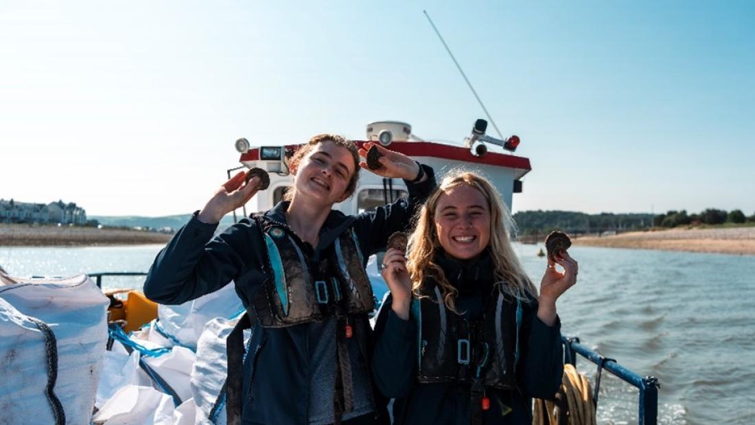 Two scientists holding oysters
