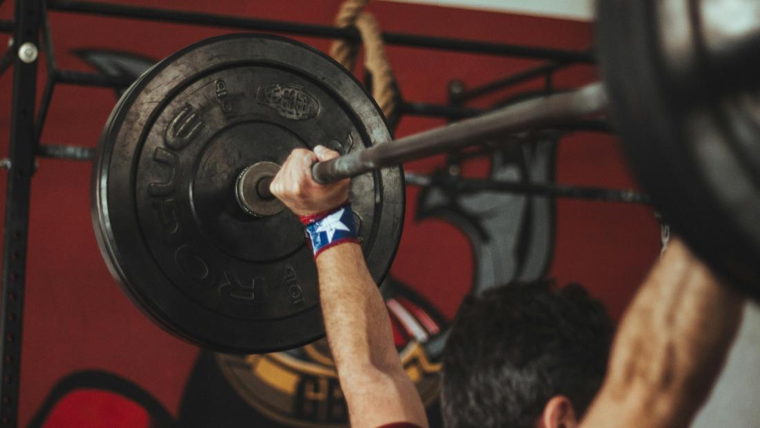Athlete lifting heavy barbell during strength training session in gym.