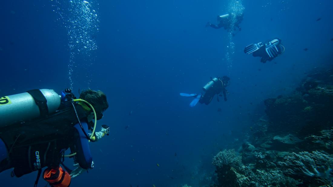 A researcher following scuba divers to collect data for video-assisted underwater observations of diver behaviour