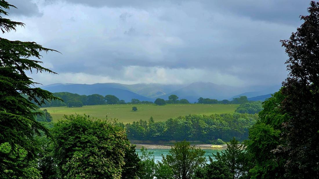 A photo showing, fields, trees and mountains over the Menai Strait