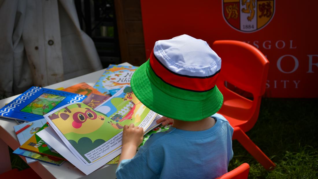 Small child wearing a hat reading books