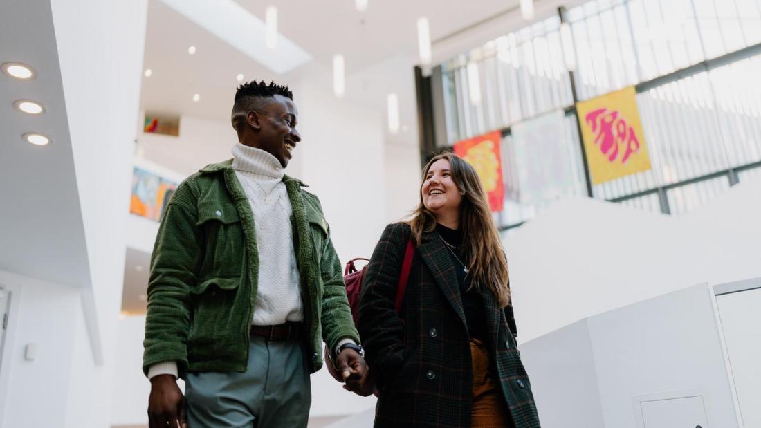 Two students walking and chatting in Pontio