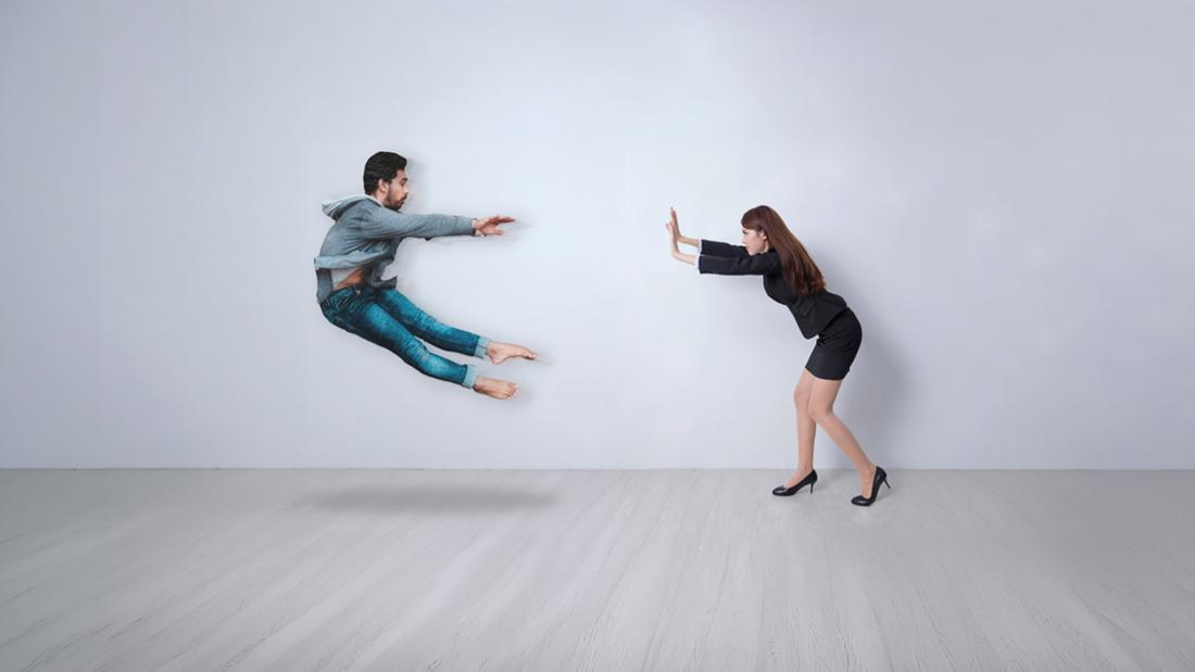A woman pushing a man away from a distance using superpowers