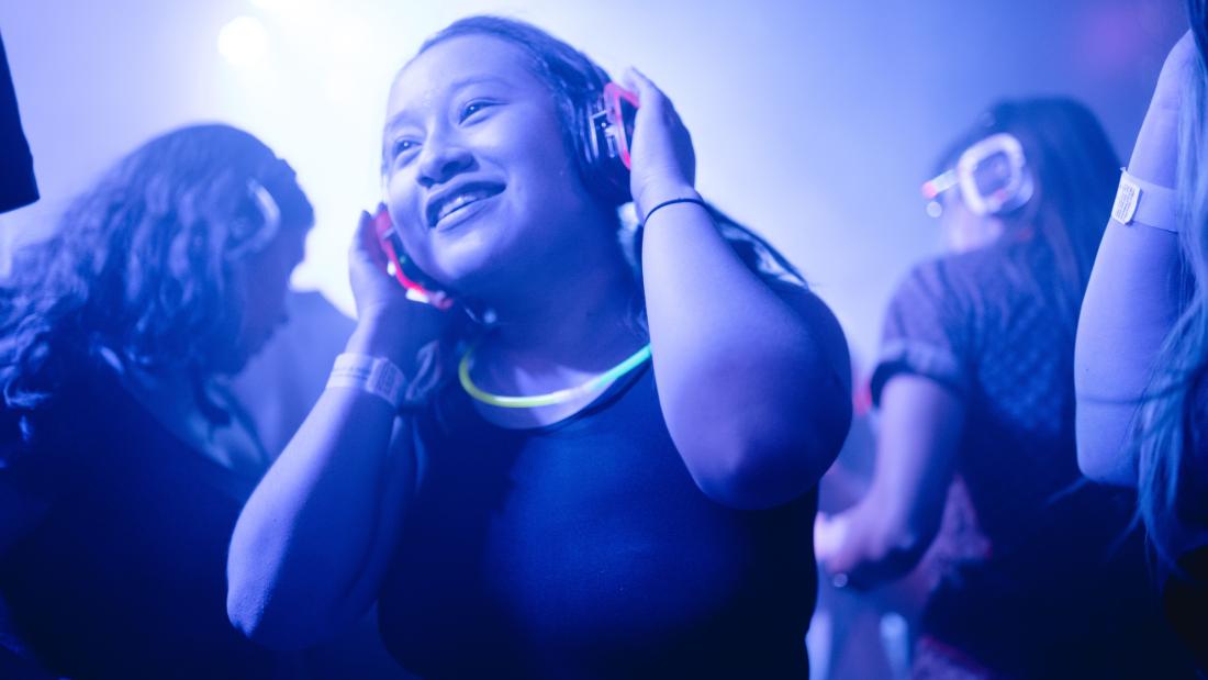People dancing at a venue. All are wearing headphones for a silent disco.
