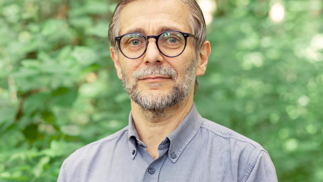 A man wearing glasses standing for a photo