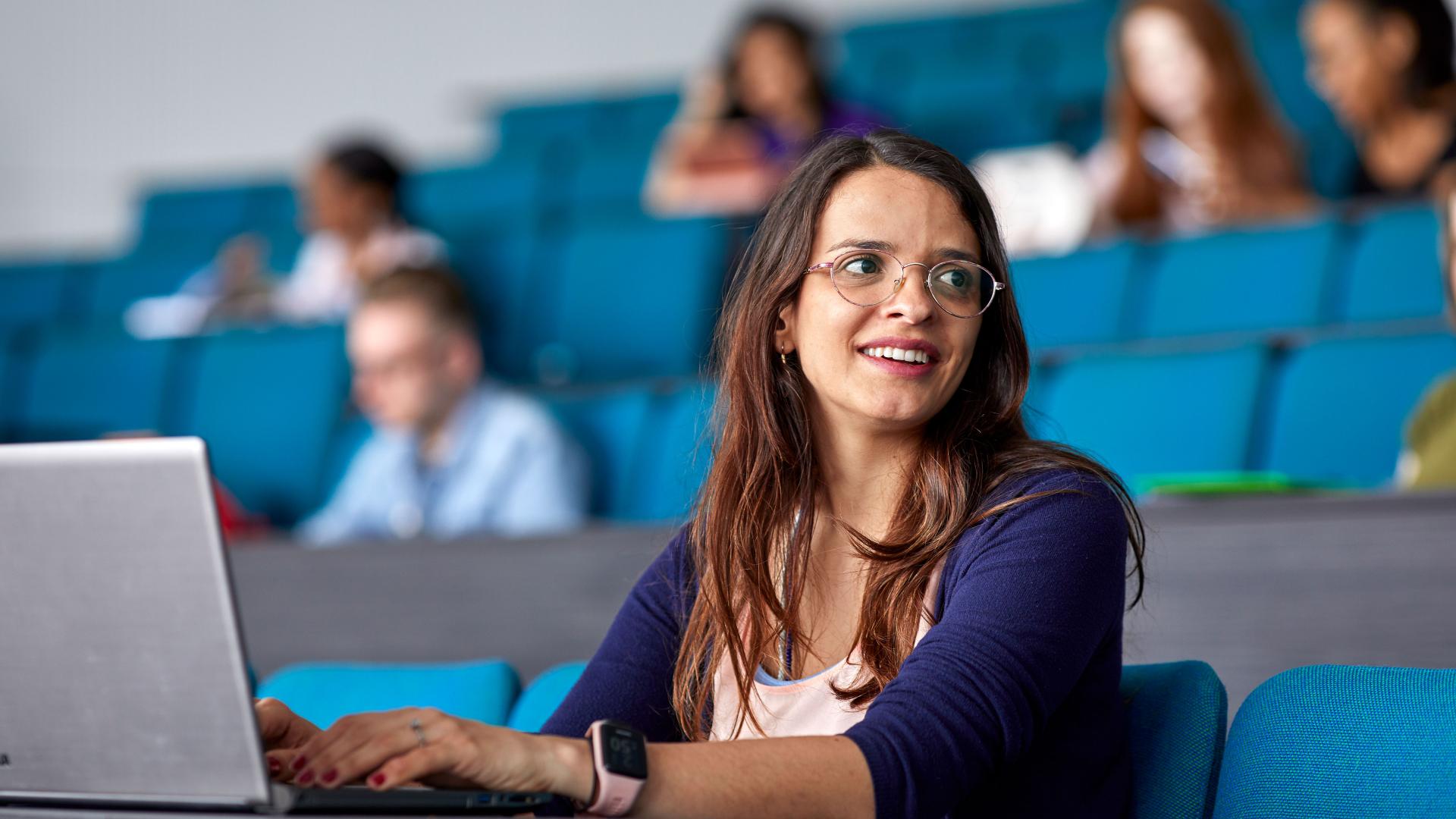 A student taking notes on her laptop in a lecture