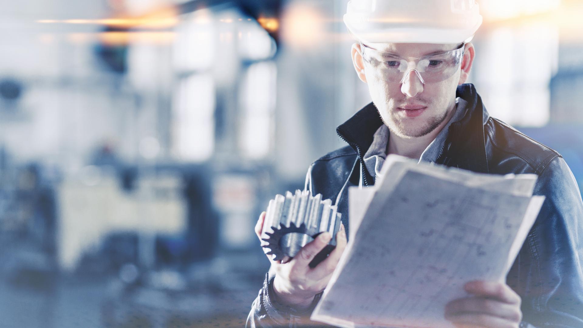 Engineer holding a engineering part and checking paper plans