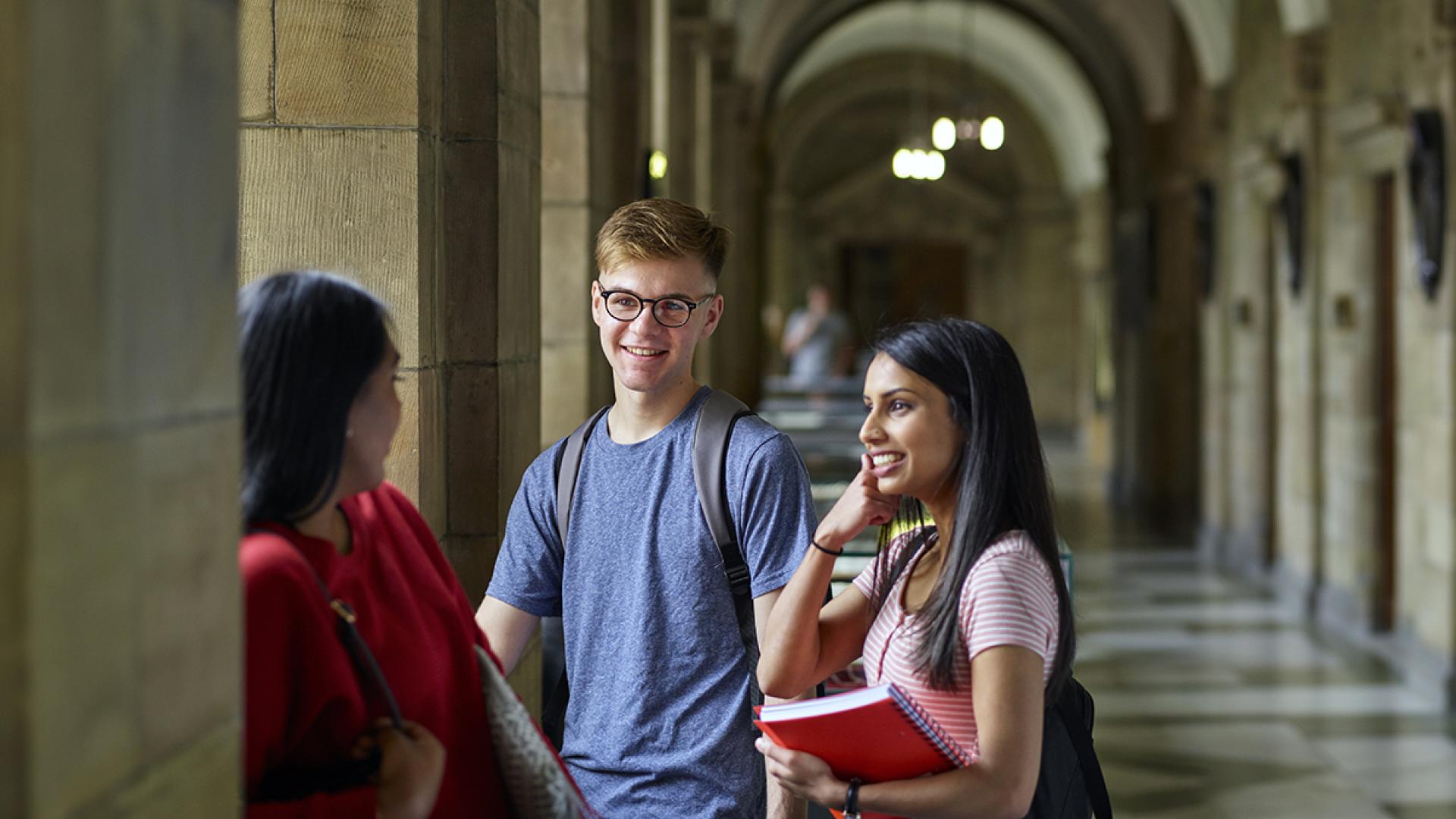 Three students chatting in the corridor in the Main Arts building