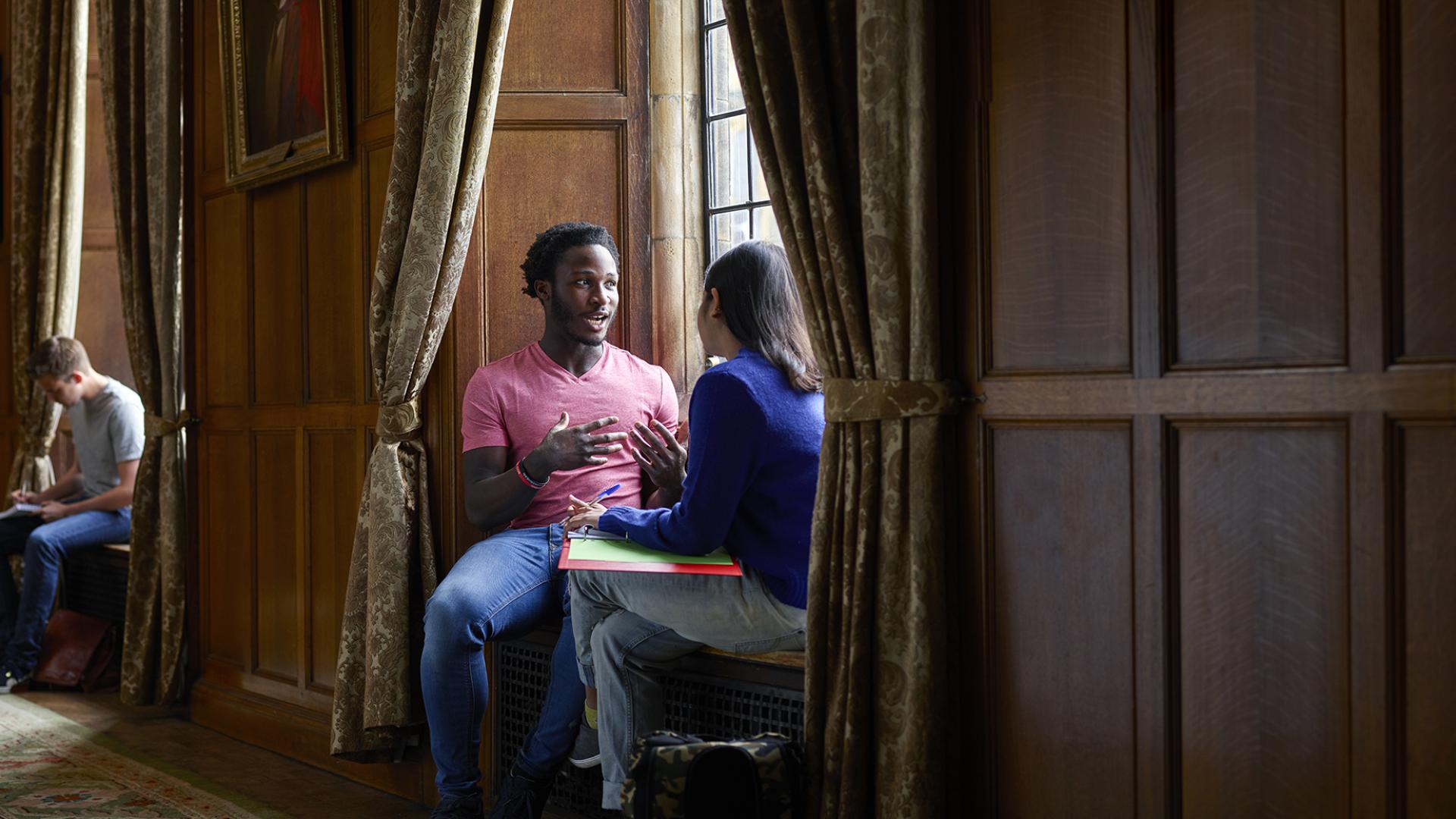 Two students chatting sitting in a window seat